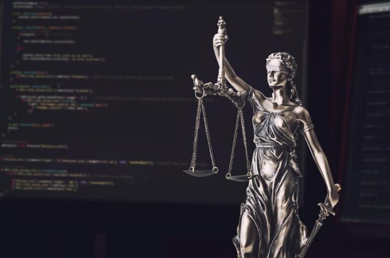 Image is of a Lady Justice statue in front of computer code, concept of digital technology and deepfake laws in Tennessee.