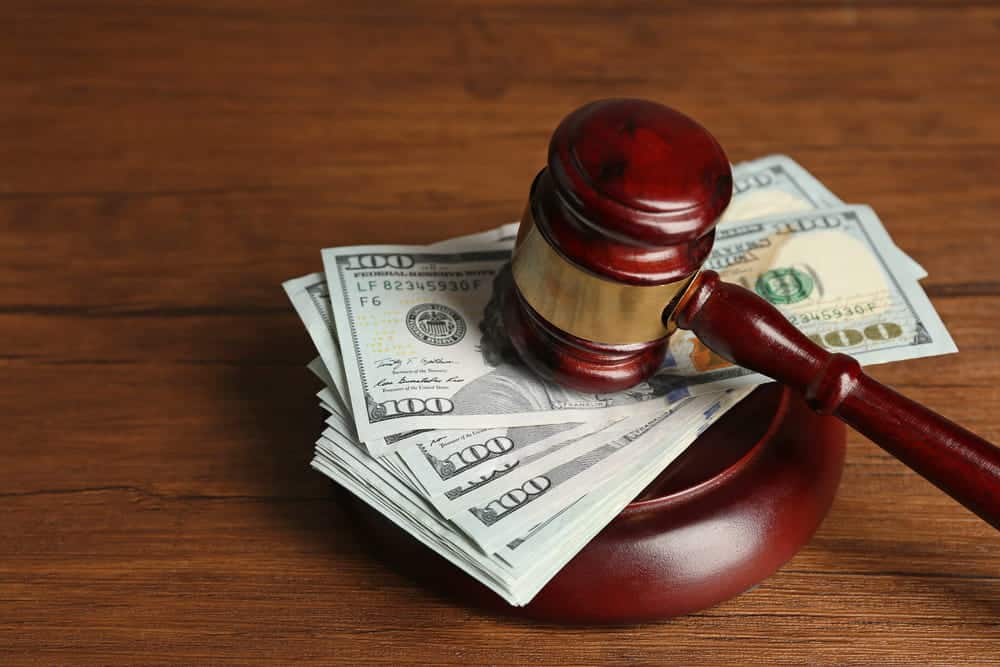 Image of a wooden judge's gavel resting on stacks of hundred-dollar bills, representing potential financial compensation in KY mass torts cases.