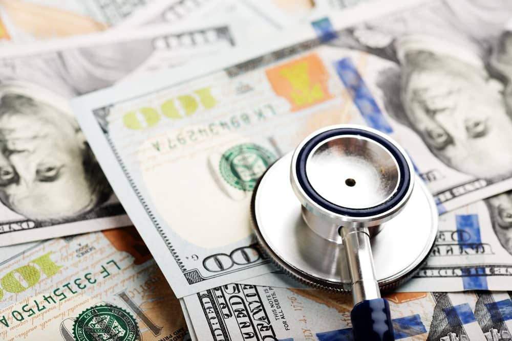 Image is of a medical stethoscope resting on American dollar bills, representing medical expenses and healthcare costs recoverable through Ohio mass torts.